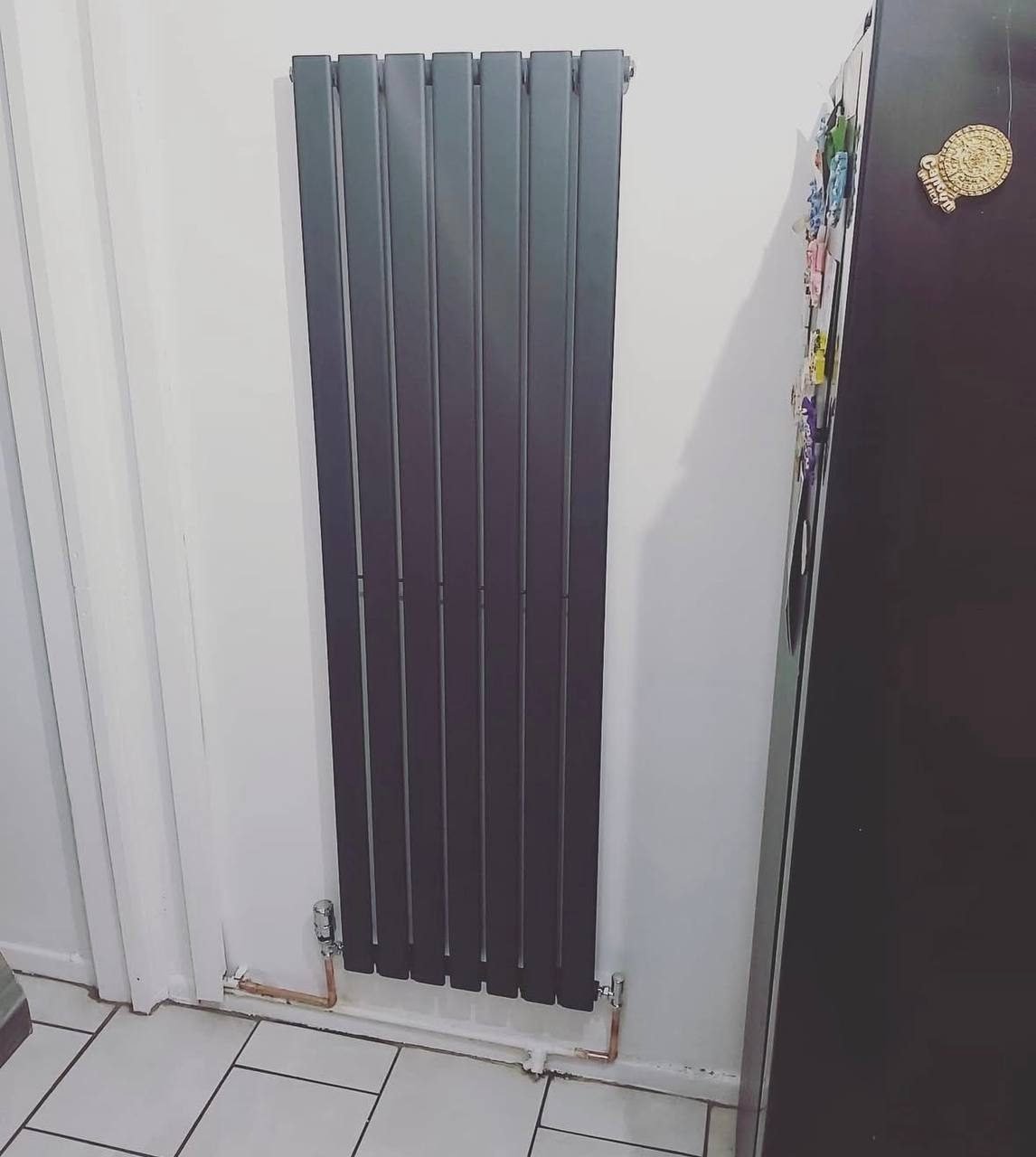 Tall anthracite vertical designer radiator fitted in a hallway